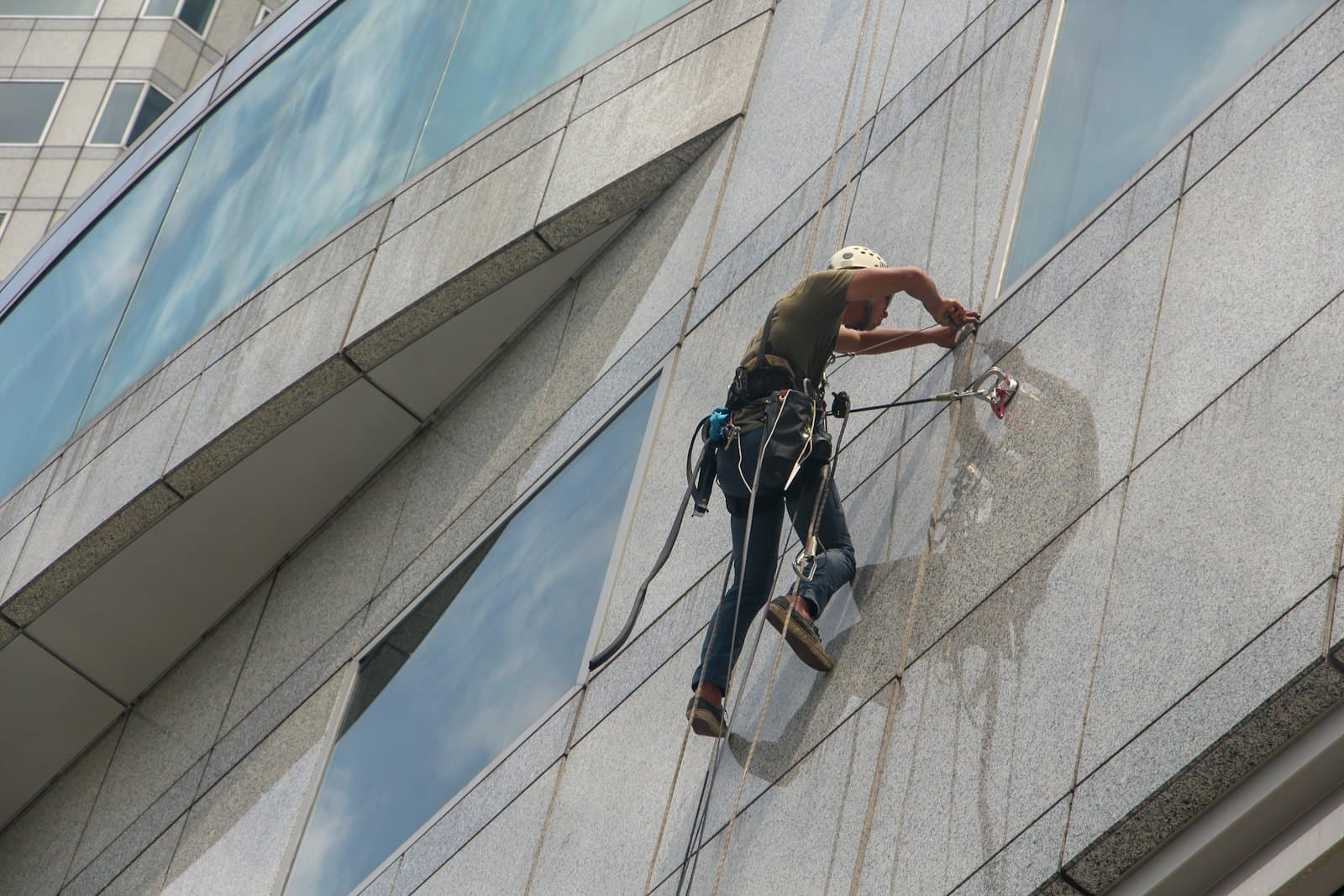 Window cleaner on ropes washing the glass facade of an office building
